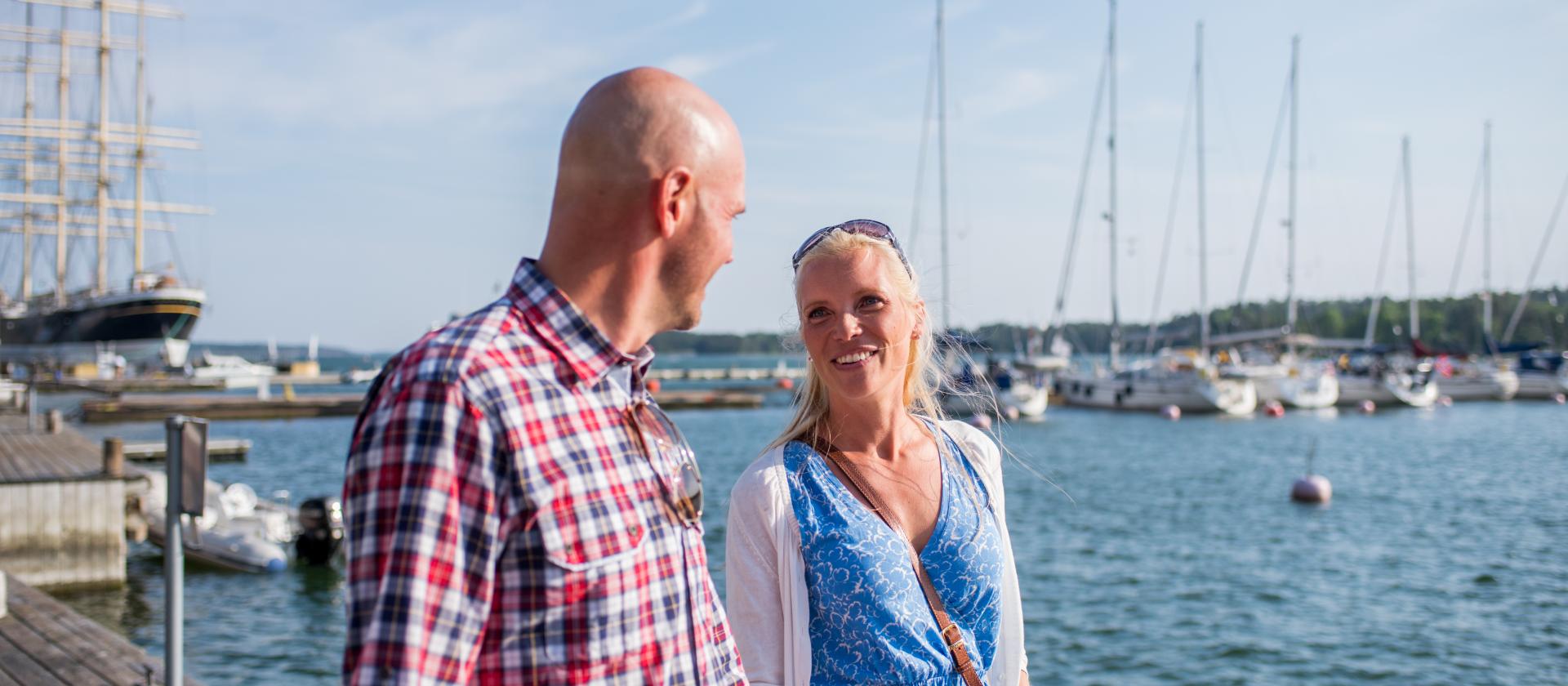 Par promenerar hand i hand vid bryggkanten i västra hamnen i Mariehamn.